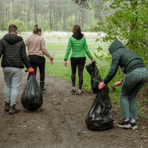 Volunteers with bags collecting litter in a forest cleanup
