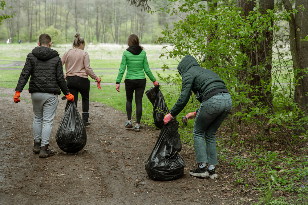 Volunteers with bags collecting litter in a forest cleanup