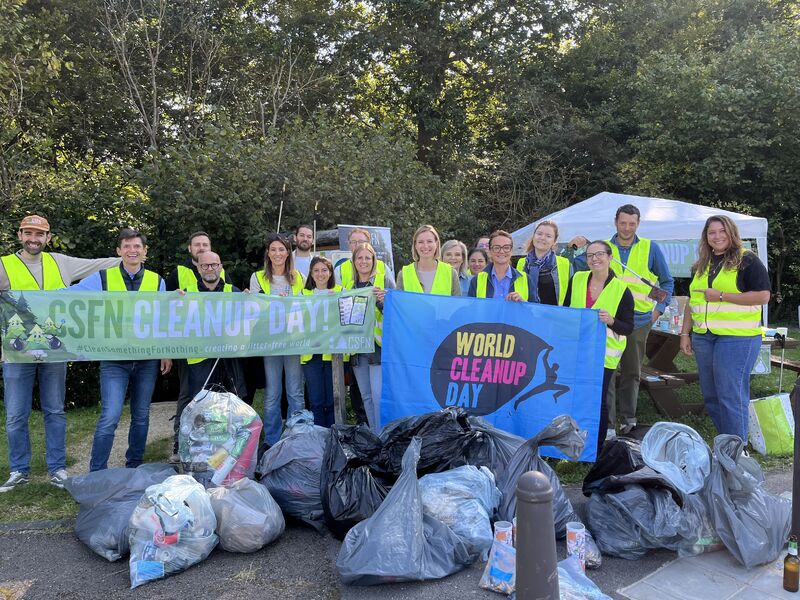 A team taking part in a corporate cleanup day in a Luxembourg park, picking up litter together