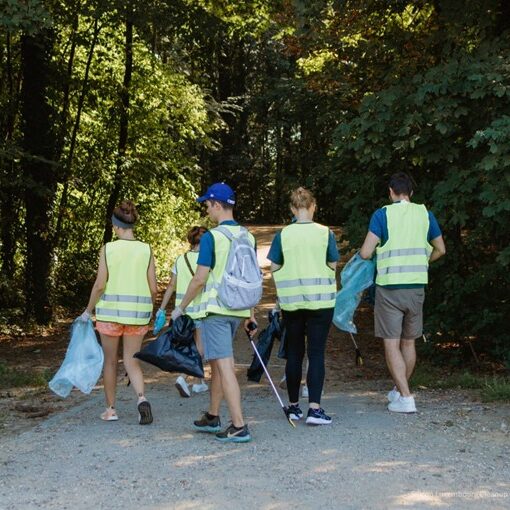 A group of people cleaning up trash in a natural outdoor setting, collecting litter into bags to restore the environment.