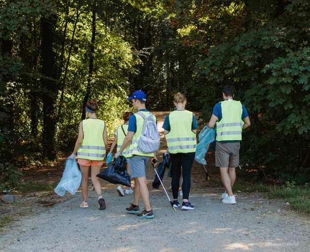 A group of people cleaning up trash in a natural outdoor setting, collecting litter into bags to restore the environment.