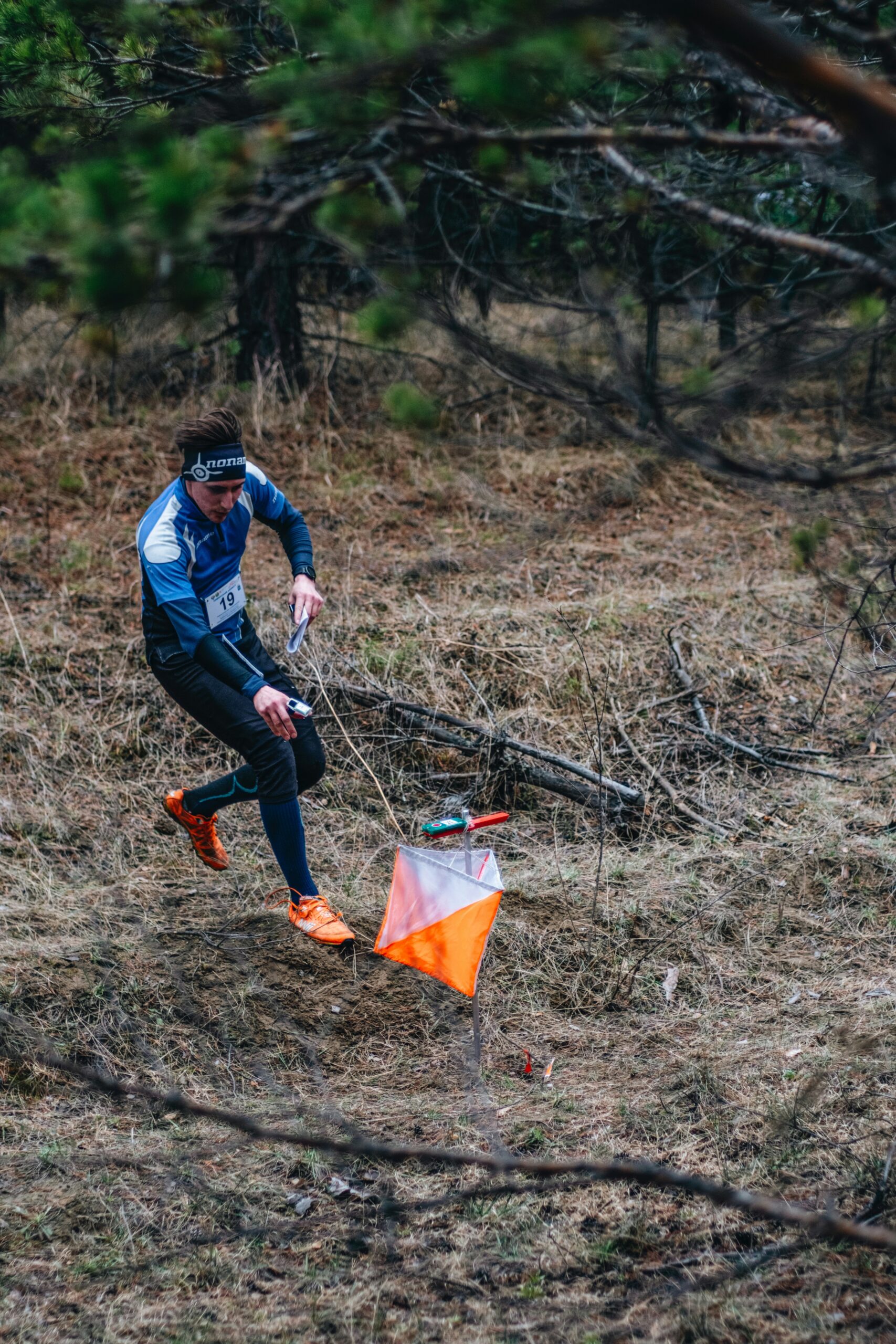 A runner picking up a plastic bottle mid-jog on a coastal path, illustrating plogging in action,