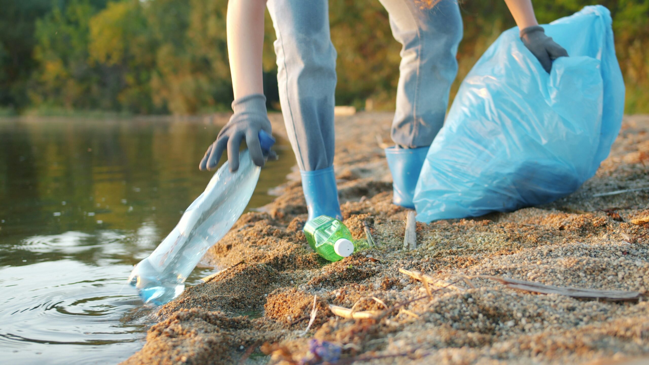 A runner mid-stride on a city or coastal path, holding a small trash bag and picling up plastic bottle ilustrating plogging.
