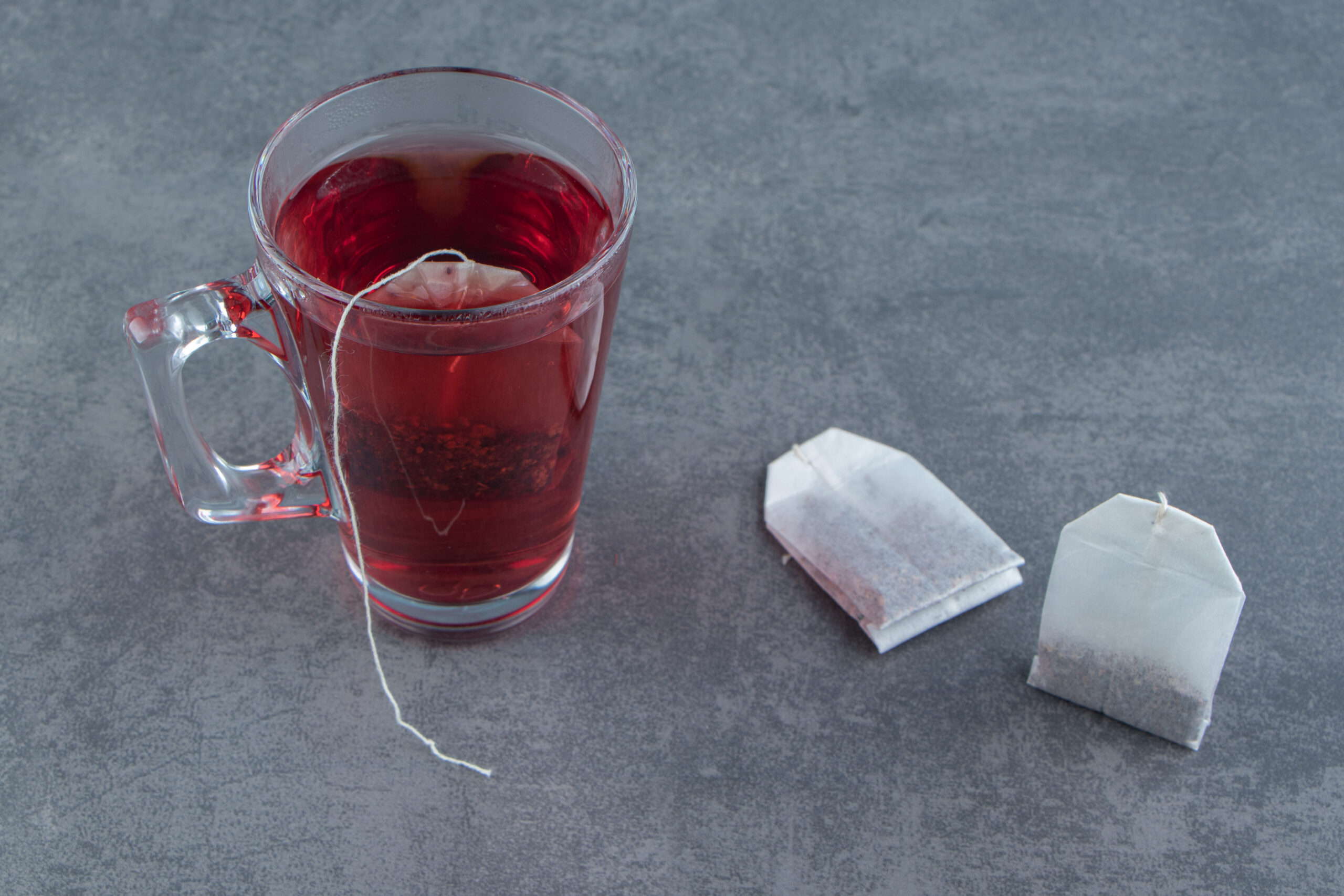 A glass cup of rosehip tea on marble background as an ilustration of hidden plasttics.